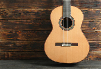Beautiful six - string classic guitar against wooden background, space for text