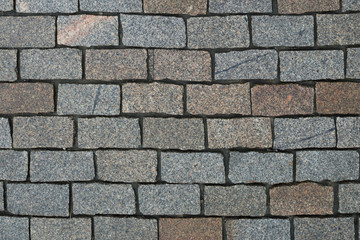 Top view on stone road close up. Pavement of granite. Brown square cobblestone sidewalk. Mock up or vintage grunge texture.
