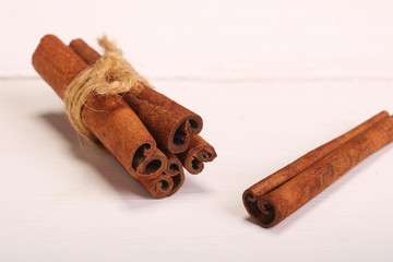 Ground cinnamon, cinnamon sticks, tied with jute hempen rope on wooden white background, selective soft focus