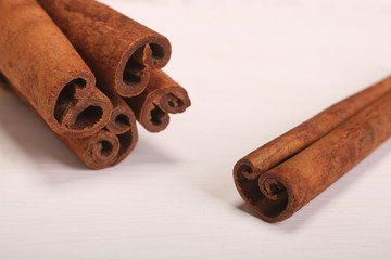 Ground cinnamon, cinnamon sticks, tied with jute hempen rope on wooden white background, selective soft focus