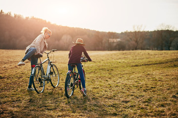 Mother and daughter with bicycles on countryside.