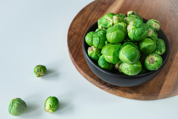 fresh organic Brussels sprouts in black bowl, white background