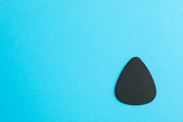 Black guitar pick on color background, space for text