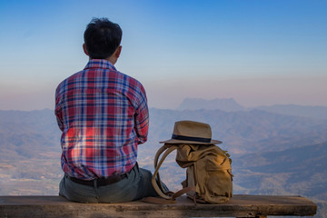 Fototapeta premium Young attractive man sitting in the forest and resting during hiking.