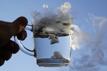 The origin of the storm in a glass of water. A cup of water against the blue sky. Sunlight. Shadows...