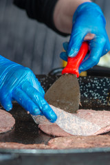 Cooking burgers on a griddle wearing blue gloves to meet food hygiene standards