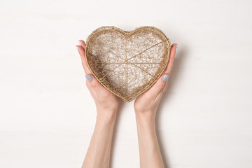 Female hands hold metal wire transparent box in the shape of a heart isolate on white background