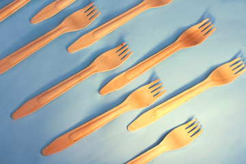 Disposable ecological wooden bamboo forks pattern on a blue background. Environment friendly flat lay