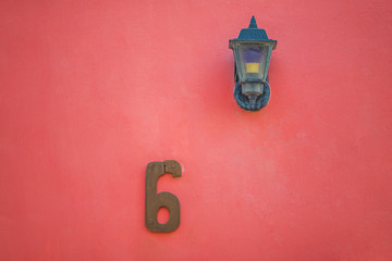 Red lamp and digit six 6 on red wall.
