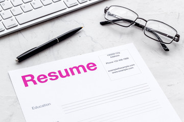 Create CV concept with pen, glasses, keyboard on white desk top view