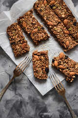Healthy sugar free dessert. Oatmeal granola bars with almonds and amaranth seeds in baking paper on concrete background top view