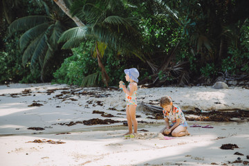 Two little sisters playing with the sand on the beach