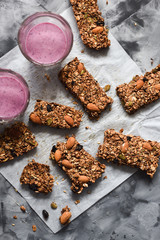 Healthy vegetarian food. Oatmeal granola bars with almonds and amaranth served with blueberry smoothie on concrete background