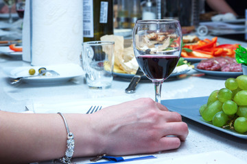 One of partying girls clinking flutes with sparkling wine. Girls hand with bracelet hold a glass of red wine