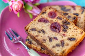 Fruitcake or cupcake on a pink plate. Cooking and dessert. Slices muffins with berry and blurry bouquet of roses. Soft focus. Macro and top view.