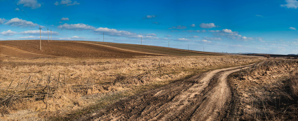 The road with dry grass on the background of hills on a sunny day in spring.