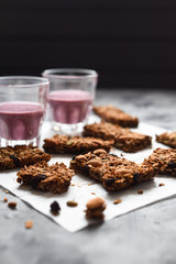 Healthy vegetarian food. Energetic granola bars with oats, almonds and amaranth served with blueberry smoothie on dark background