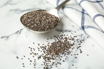 Spoon with chia seeds on marble table, closeup