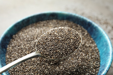Spoon with chia seeds over bowl, closeup