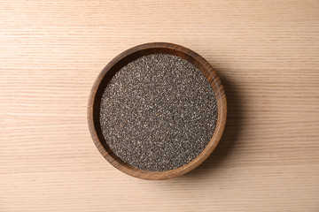 Bowl with chia seeds on wooden background, top view