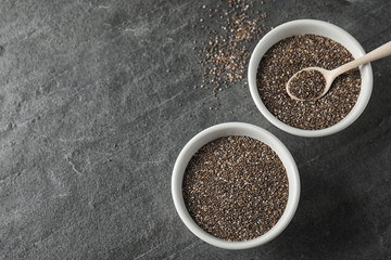 Bowls with chia seeds on grey background, flat lay. Space for text