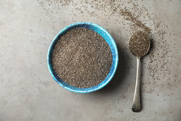 Bowl and spoon with chia seeds on grey background, flat lay