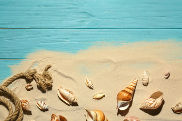 Flat lay composition with seashells, beach sand and space for text on wooden background