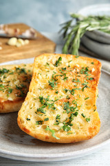 Plate with delicious homemade garlic bread on table