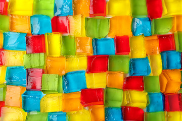 Tasty colorful jelly cubes as background, top view
