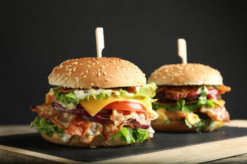Tasty burgers with bacon served on board