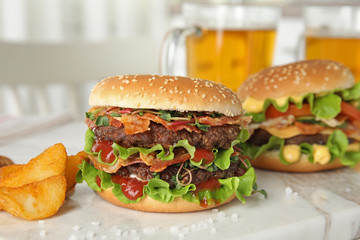 Tasty burgers with bacon and fried potatoes served on board