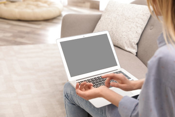 Fototapeta premium Young woman using video chat on laptop in living room, closeup. Space for design