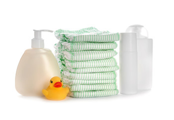 Stack of disposable diapers and baby accessories on white background