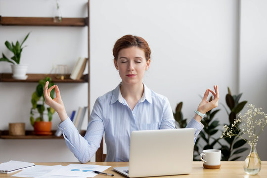 Calm healthy business woman meditate relaxing at office desk