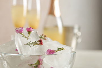 Bowl with floral ice cubes on blurred background, closeup. Space for text
