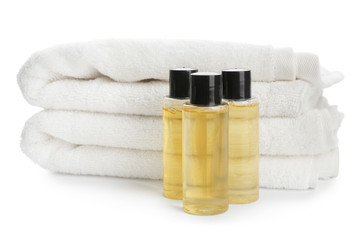 Fototapeta na wymiar Mini bottles with cosmetic products and towels on white background. Hotel amenities