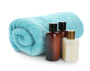 Mini bottles with cosmetic products and towel on white background. Hotel amenities