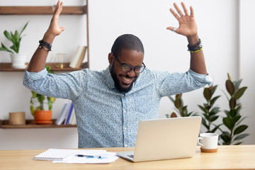 Euphoric overjoyed african businessman happy to read great online news
