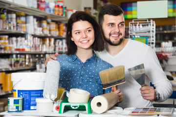 happy loving couple demonstrating tools for house renovating in paint store