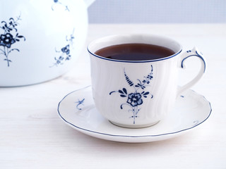Cup of tea and tea pot in background