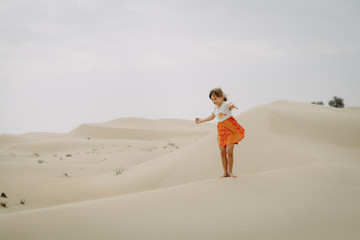 Little girl walks in sand dunes