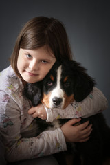 Girl child hugging puppy bernese mountain dog