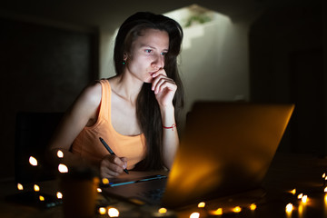 Portrait of young designer girl working at graphic tablet on laptop. Dressed in yellow wearing glasses.