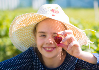 the girl helps to collect strawberry in the garden