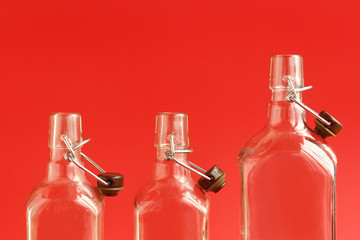 Closeup of three glass empty open bottles over red background