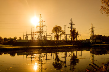 Electrical substation at sunset on the banks of the river. Silhouette. Yellow fill. Horizontal...
