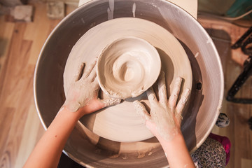 Fototapeta premium young potter hands working with clay on pottery wheel