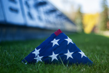 American flag on the background of grass and slab of the dead. Concept for Memorial Day and other...