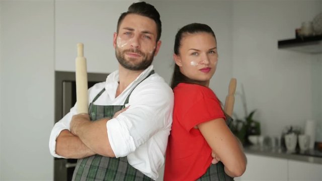 Horizontal Portrait of Surprised Female Leans At Husbands Shoulder Being Shocked That He Is Not Tired After Helping To Prepare Pizza, Has Confidence And Strength. Couple Work As Team On Kitchen.