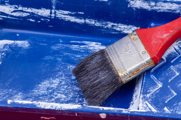 blue paint container with white paint and black brush